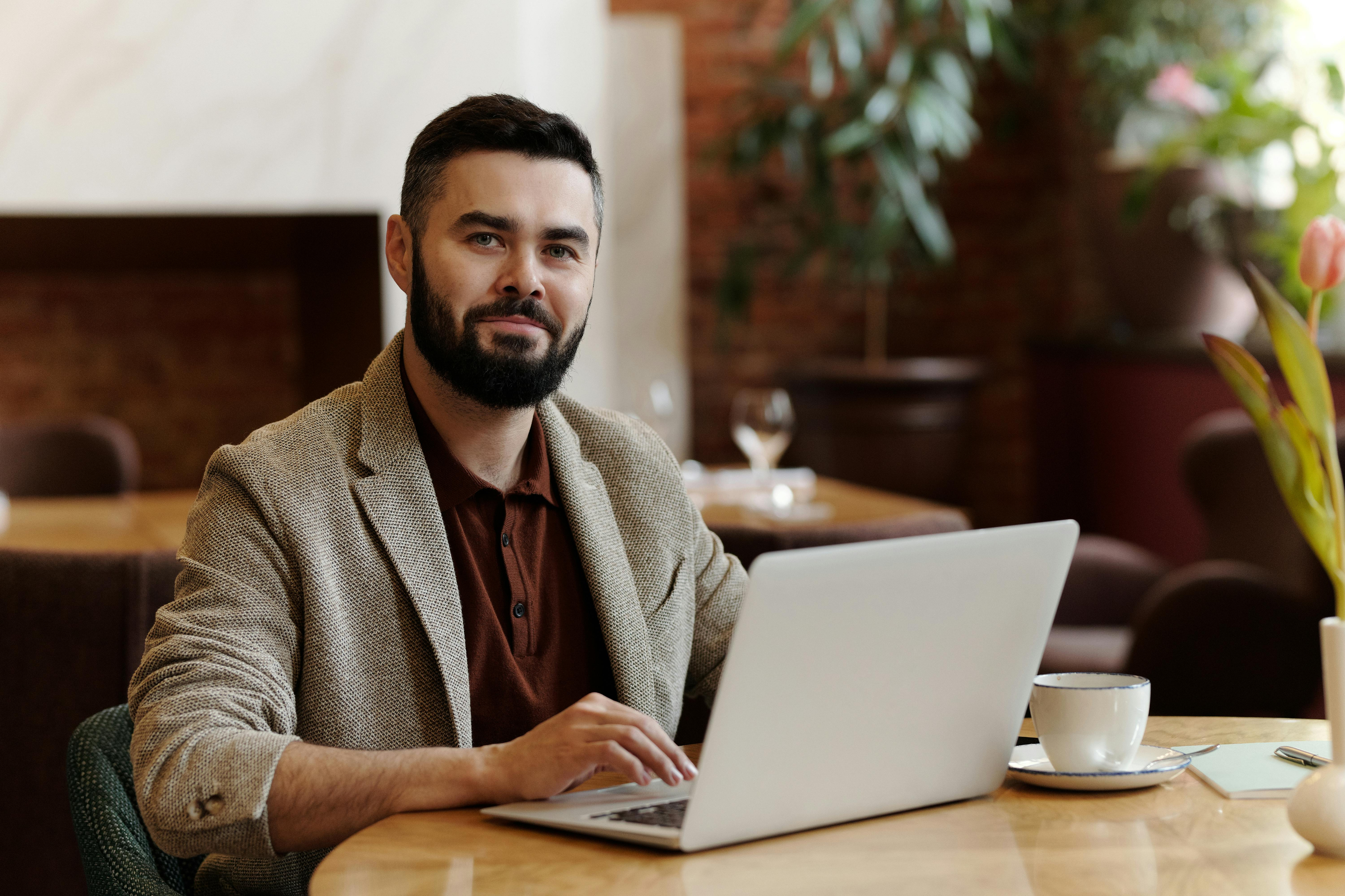 Hombre trabajando en escritorio con computador y café