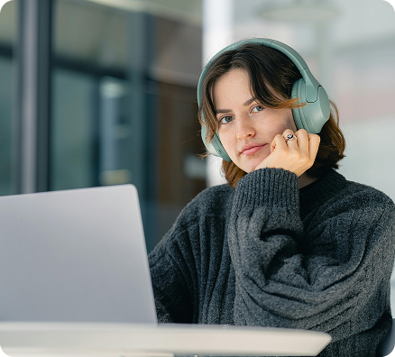 Mujer en un escritorio mirando a la camara con audifonos
