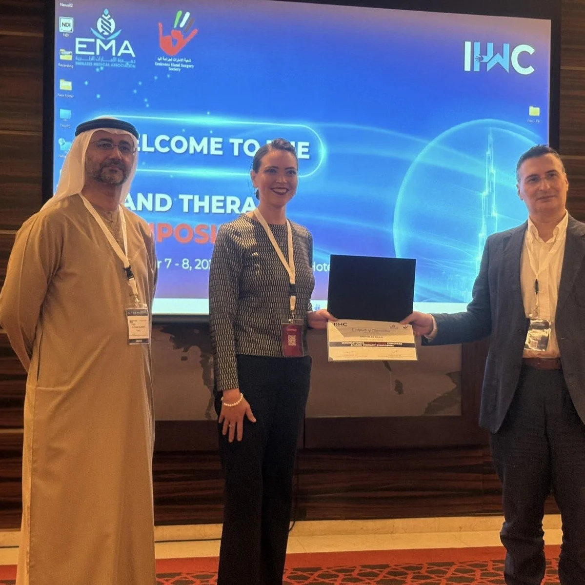 Michelle Razo Receiving a Certificate from Emirates Hand Surgery Society President & Founder, Dr. Khalid Al Awadi and Vice President, Dr. Ehab Aldlyami