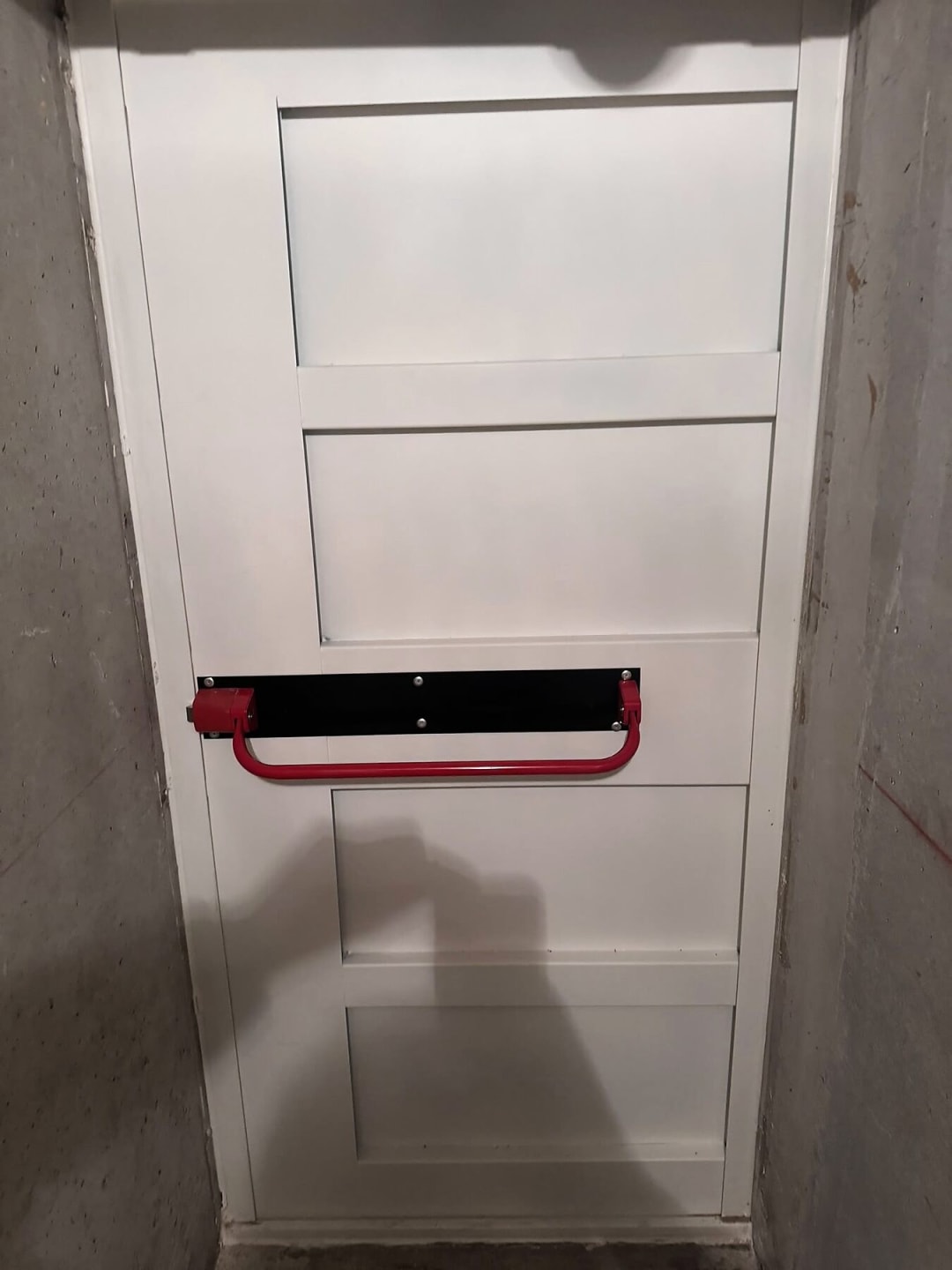 Porte de sortie de secours blanche équipée d’une barre anti-panique rouge