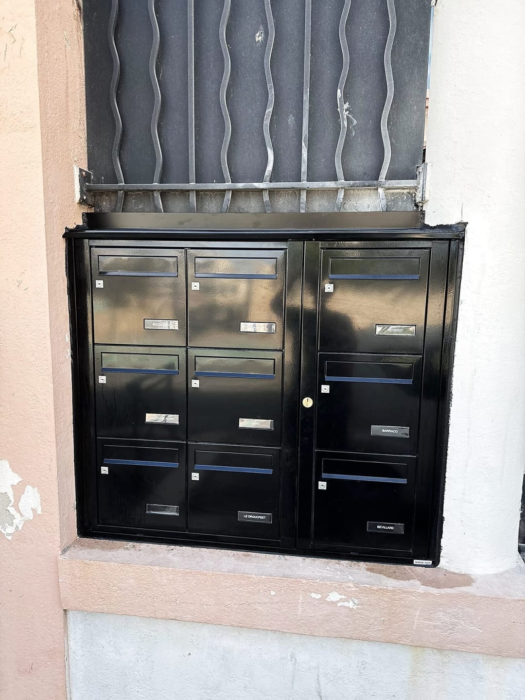 Bloc de boîtes aux lettres noires encastré dans un mur