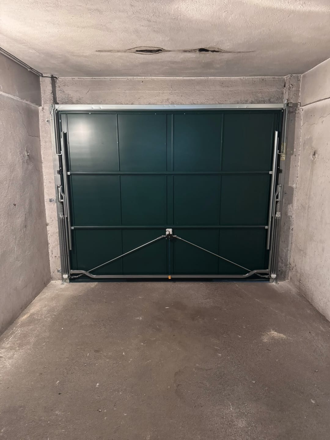 Porte de garage basculante verte vue de l’intérieur du box, avec son mécanisme