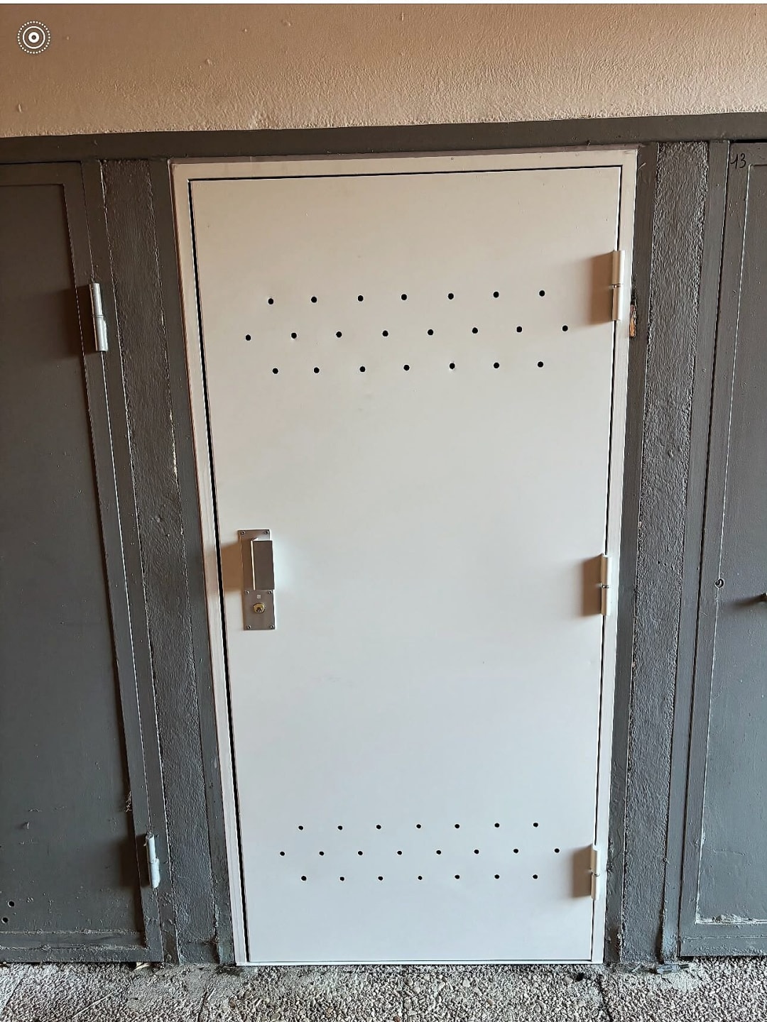 Porte métallique blanche percée de trous de ventilation