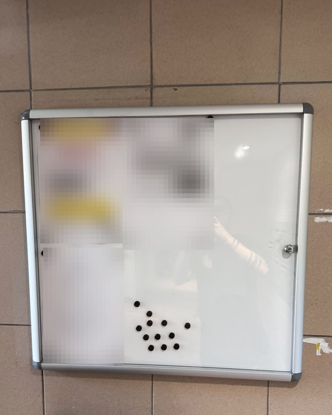 Tableau d’affichage vitré fermant à clé, posé dans un hall