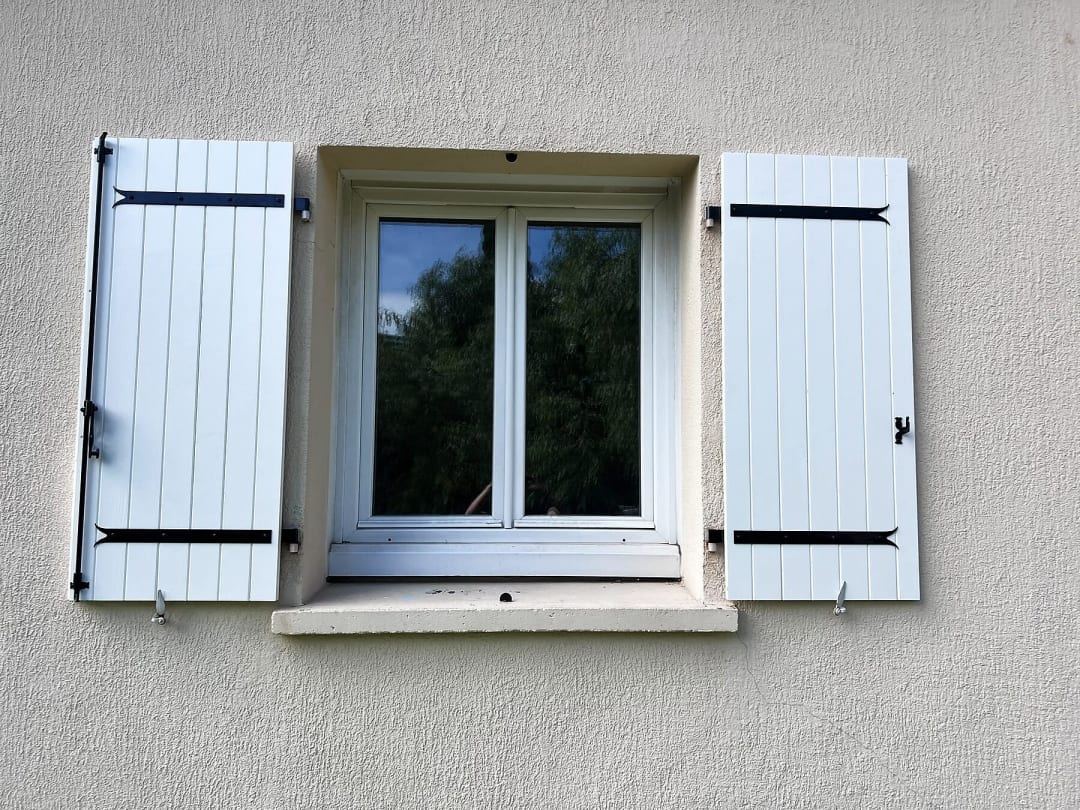 Fenêtre avec volets battants en bois, blancs, pentures noires