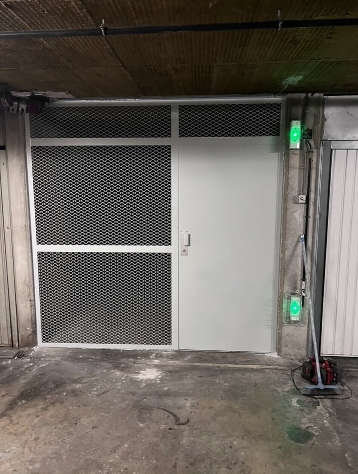 Porte métallique et panneaux en métal déployé fermant un accès de parking