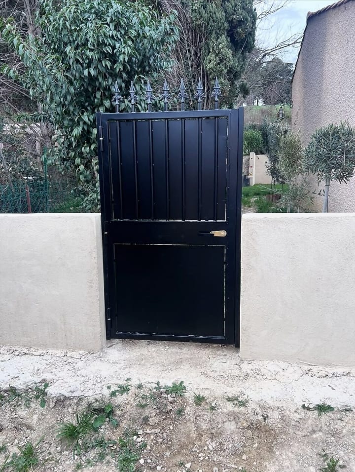 Portillon plein en acier noir dans un mur de clôture
