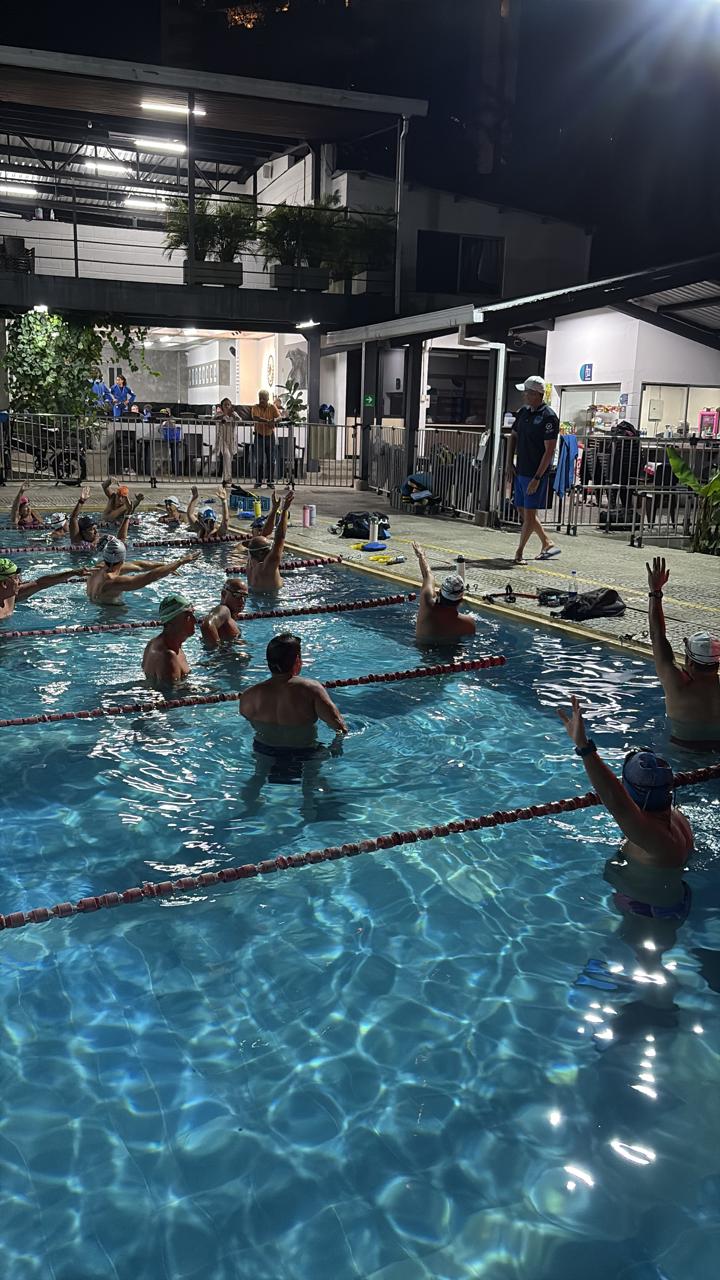 grupo de nadadores recibiendo instrucciones de su entrenador durante un evento de natación de corección de técnica
