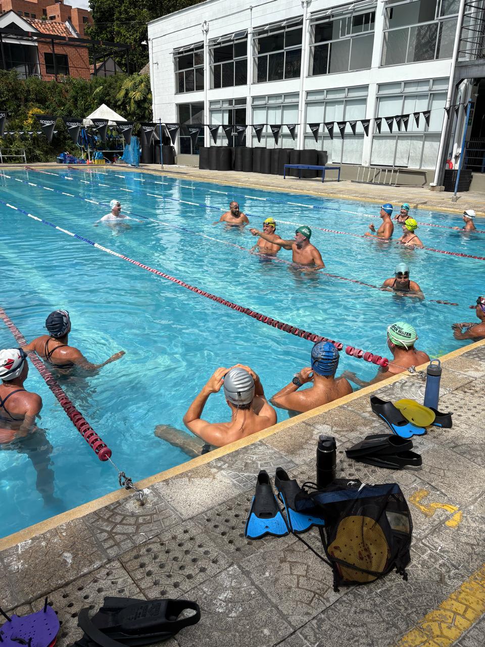 entrenador dirigiéndose a un grupo de nadadores durante un evento diurno de natación