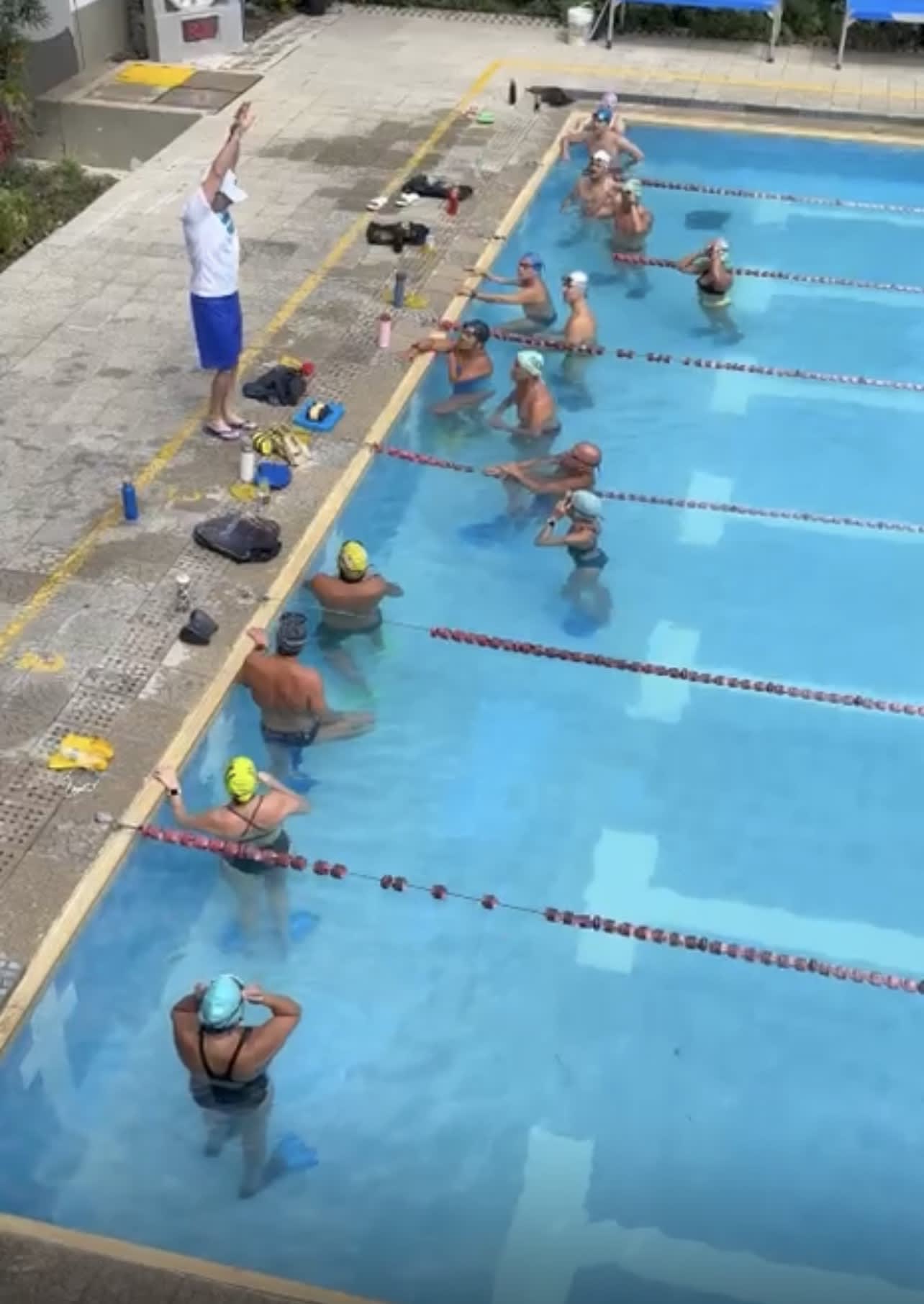 entrenador instruyendo a sus nadadores sobre la posición corporal ideal en el agua