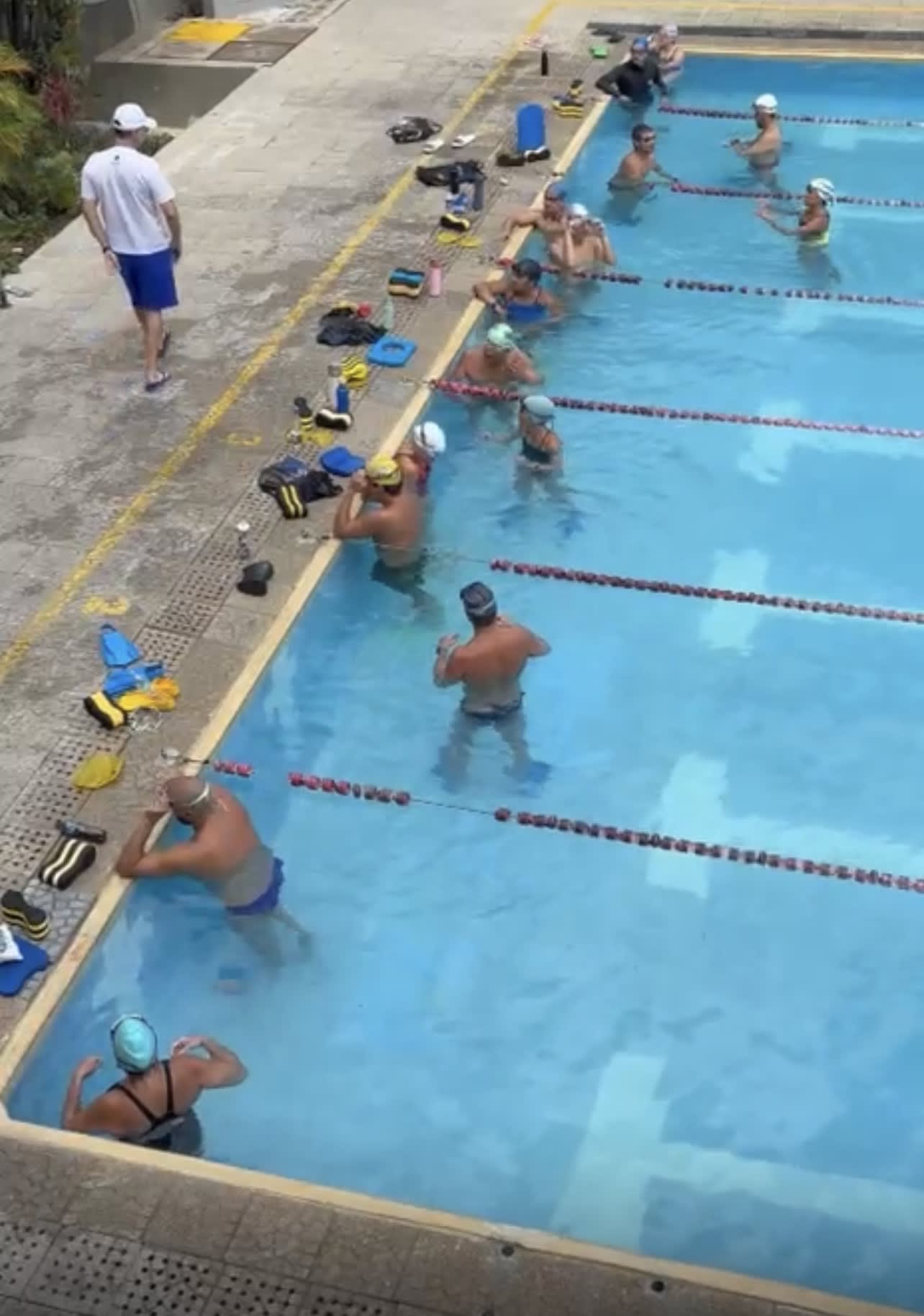 nadadores atentos al entrenador, quien está a punto de dar más instrucciones durante la clínica