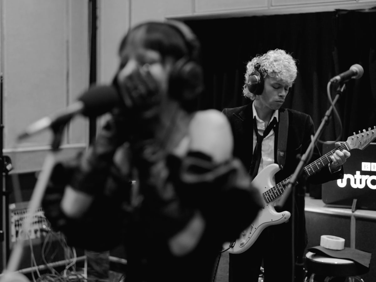 The guitarist in focus at BBC Maida Vale, Bambie Thug blurred in the foreground at the microphone