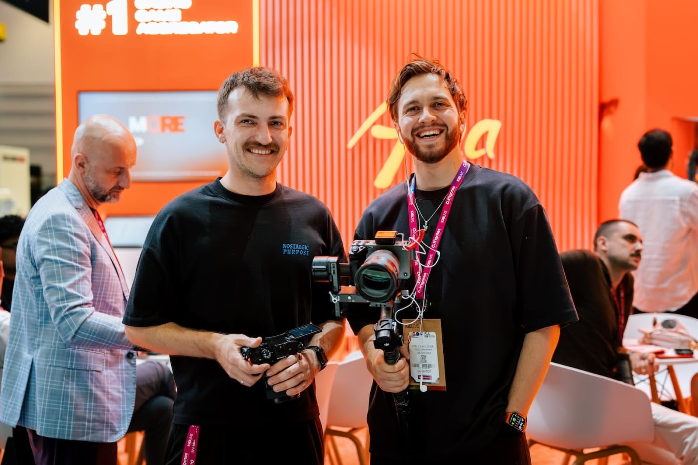 Two We Stream operators on a trade show stand, one with a stills camera and one with a camera on a gimbal