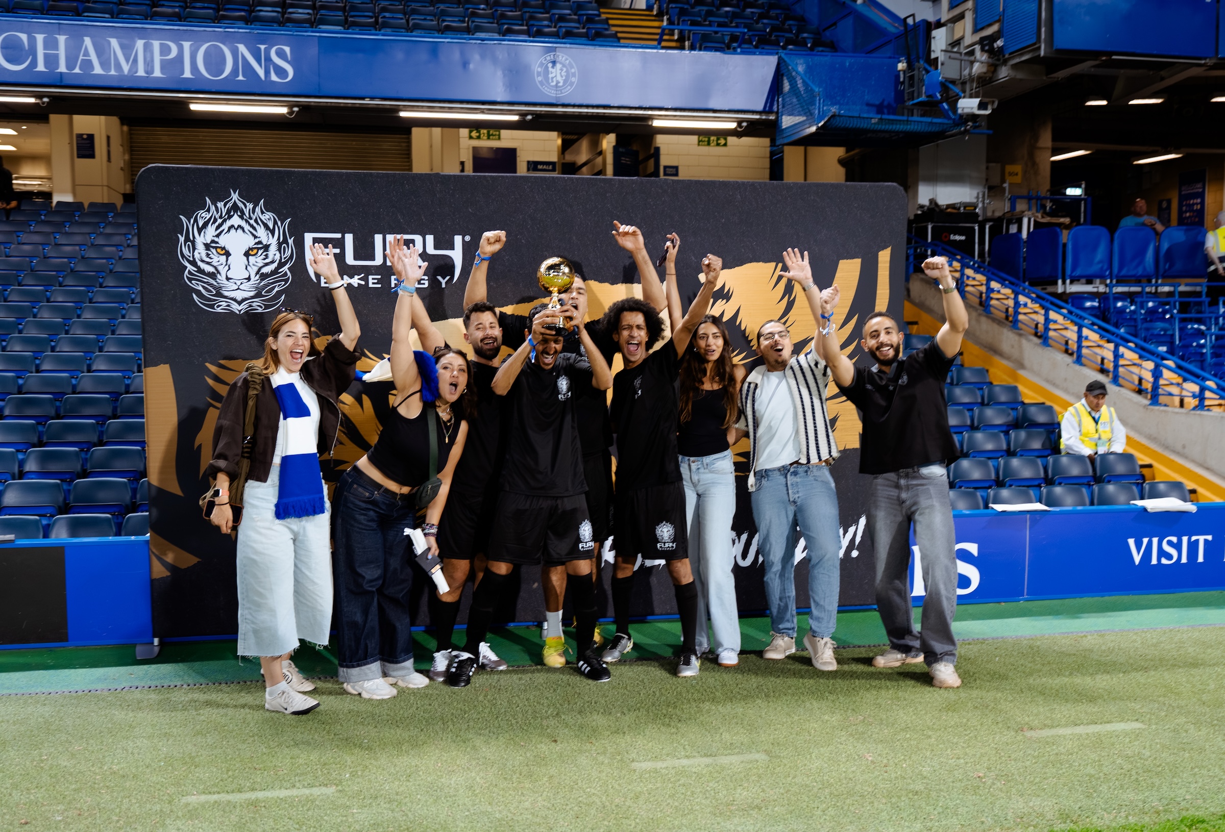 Fury Energy team group photo under the Chelsea FC Champions banner, Stamford Bridge