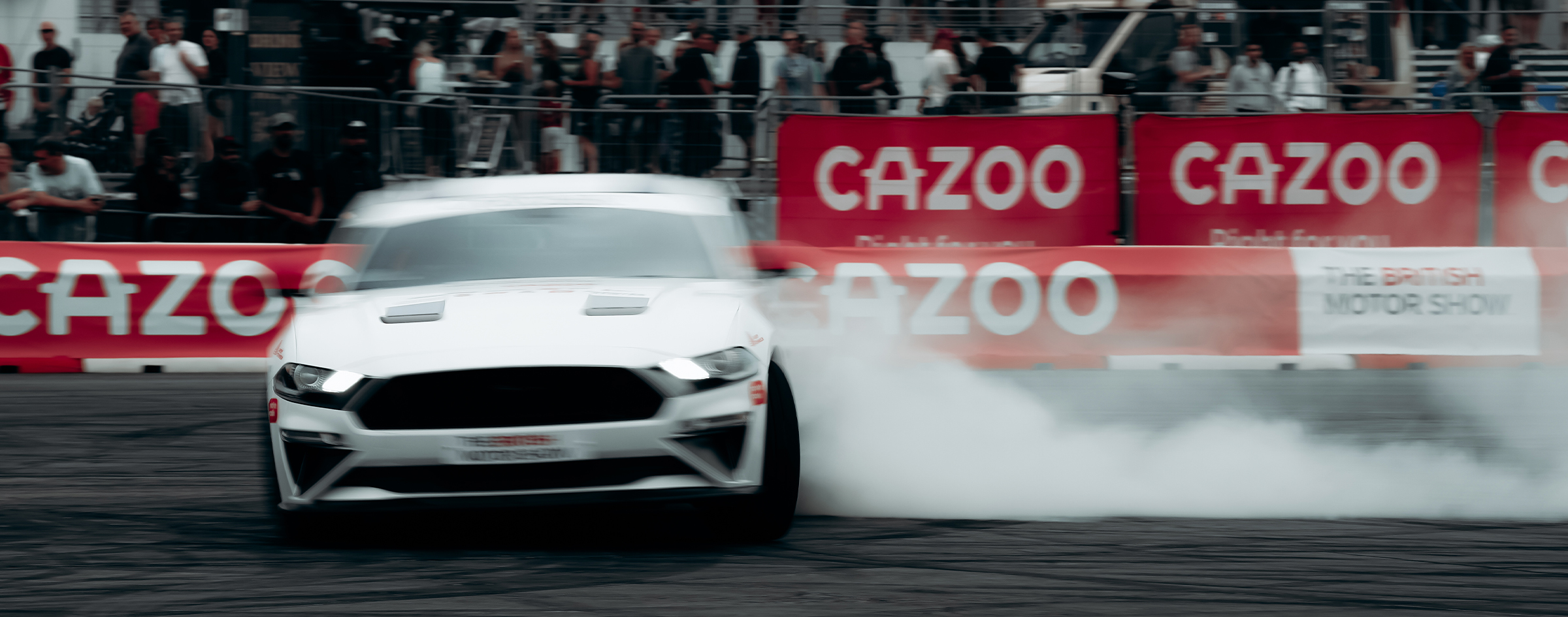 Ford Mustang drifting in front of Cazoo branding at the British Motor Show, event photography by We Stream