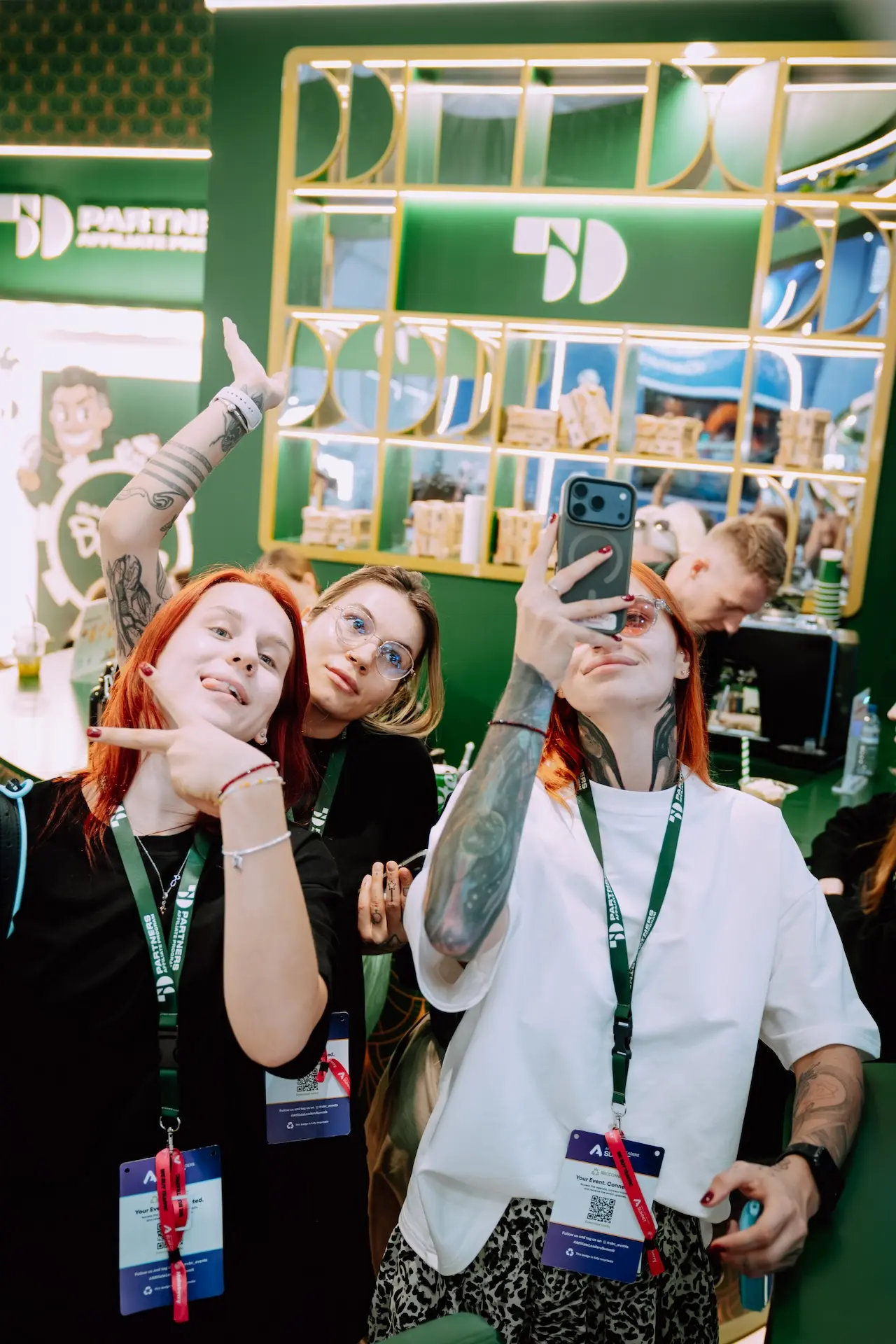 Three 50 Partners team members pulling faces for a selfie in front of the stand shelves, SBC Summit Lisbon 2026