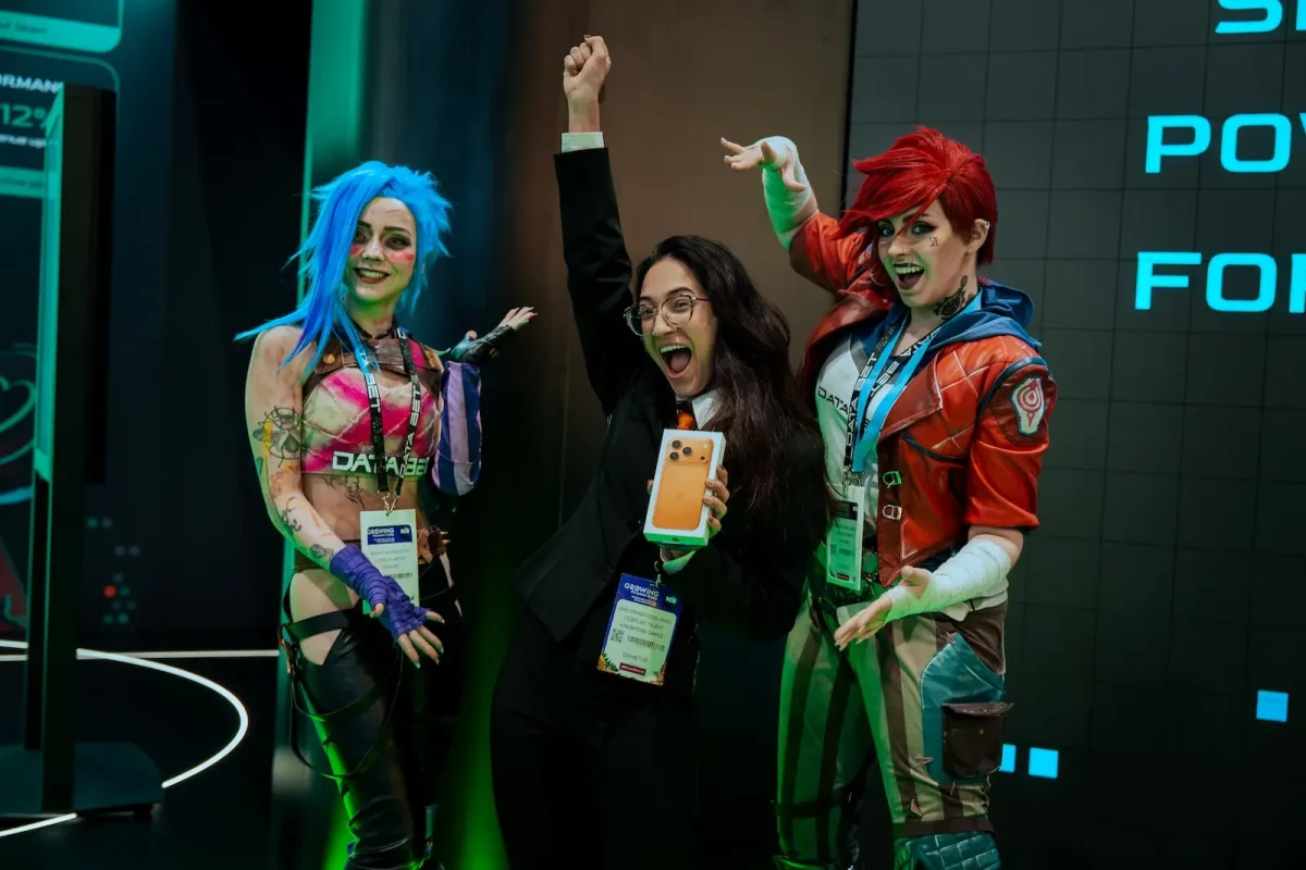 Visitor posing with Jinx and Vi cosplayers on DATA.BET's Arcane stand at ICE Barcelona 2026