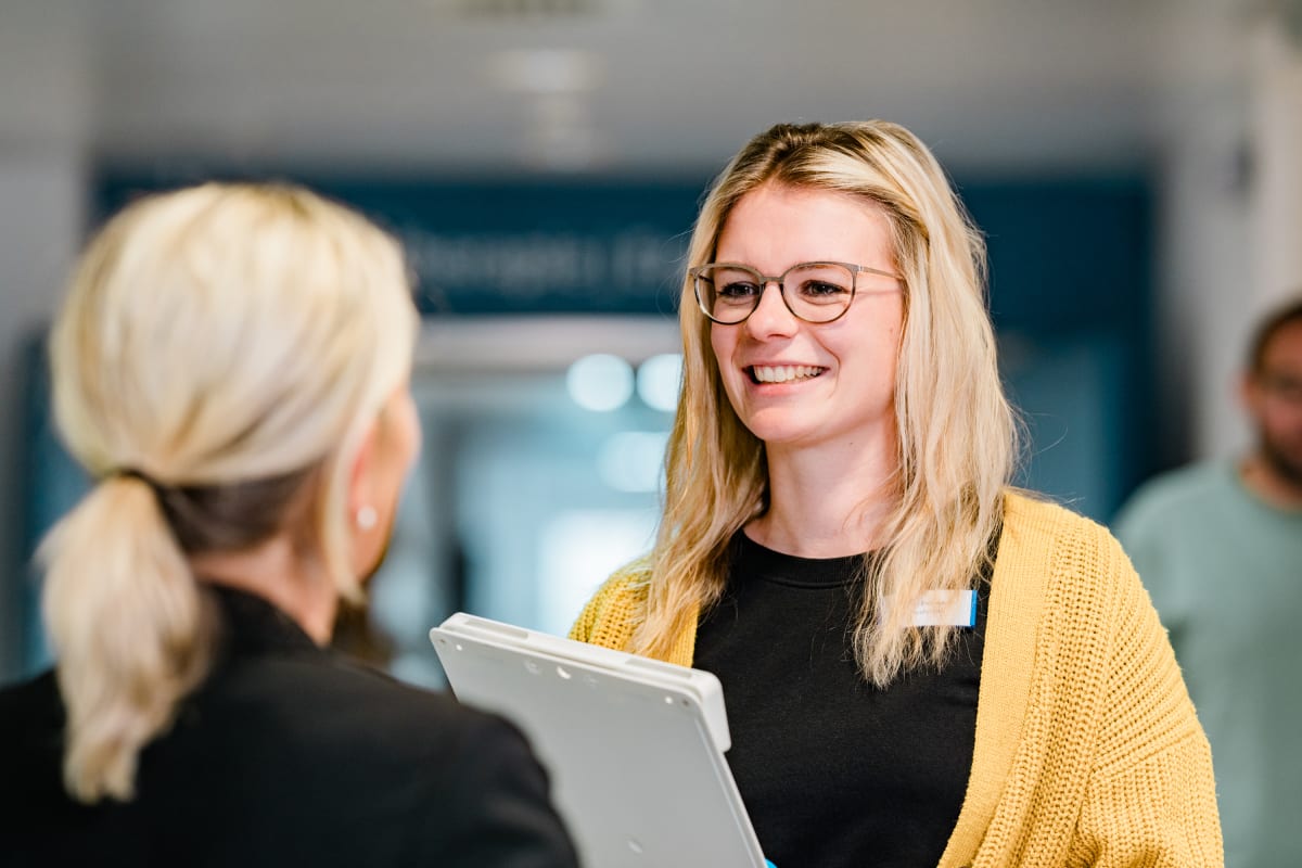 Mitarbeiterin mit Klemmbrett im Aufnahmegespräch