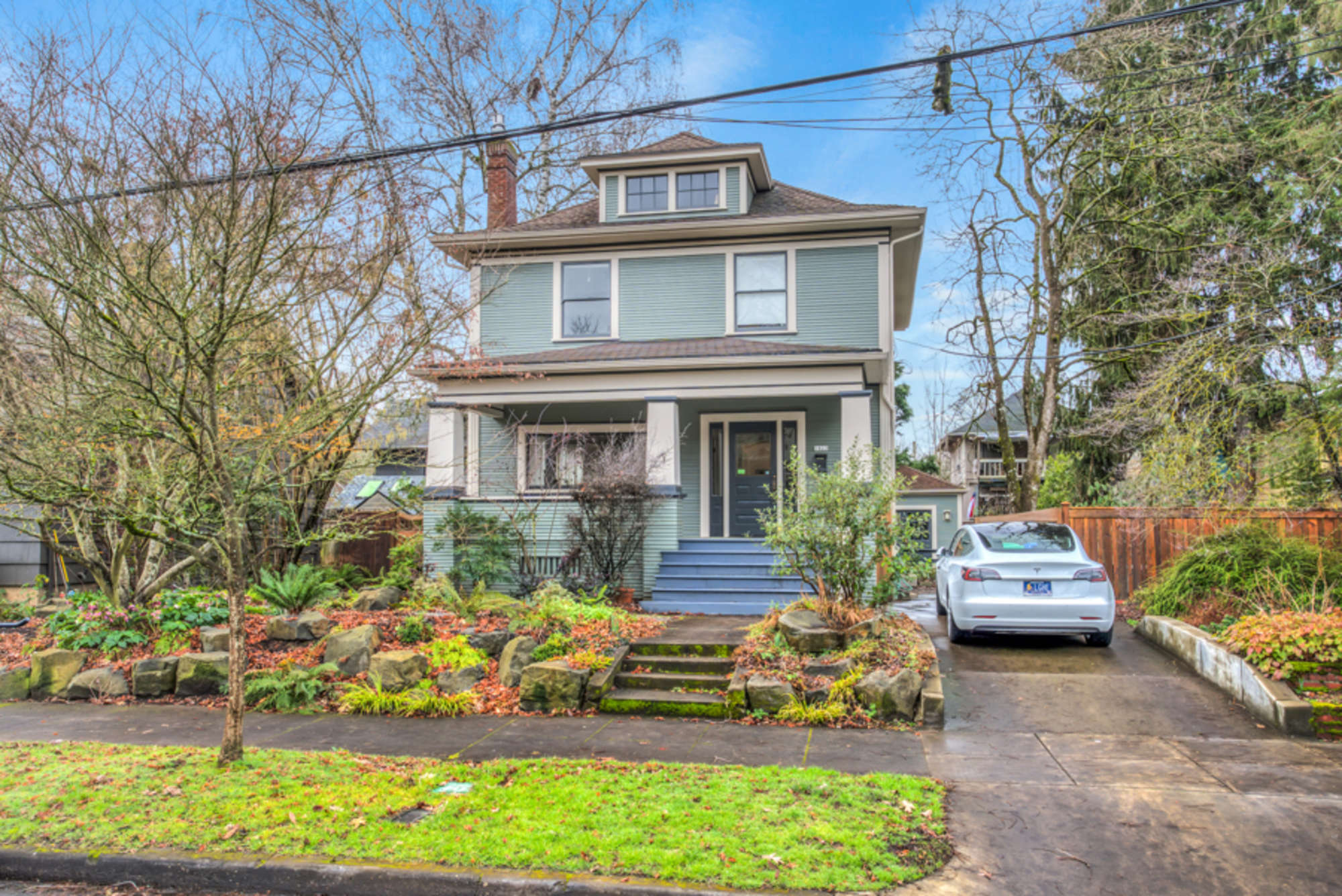 Home from the street, looking West.  Entrance is at North side of the house, behind a gate that&#39;s beyond the white car.