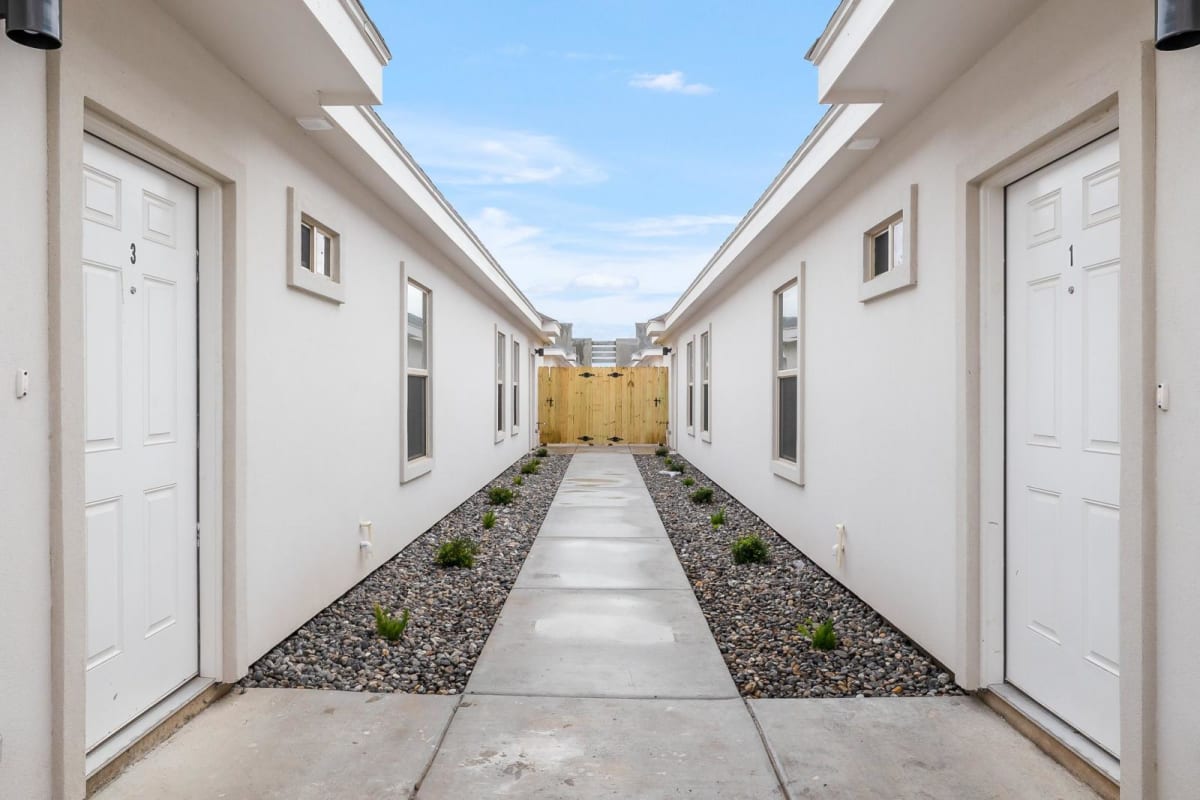 Breezeway walkway between two Verona units with a landscaped rock path and wood privacy fence