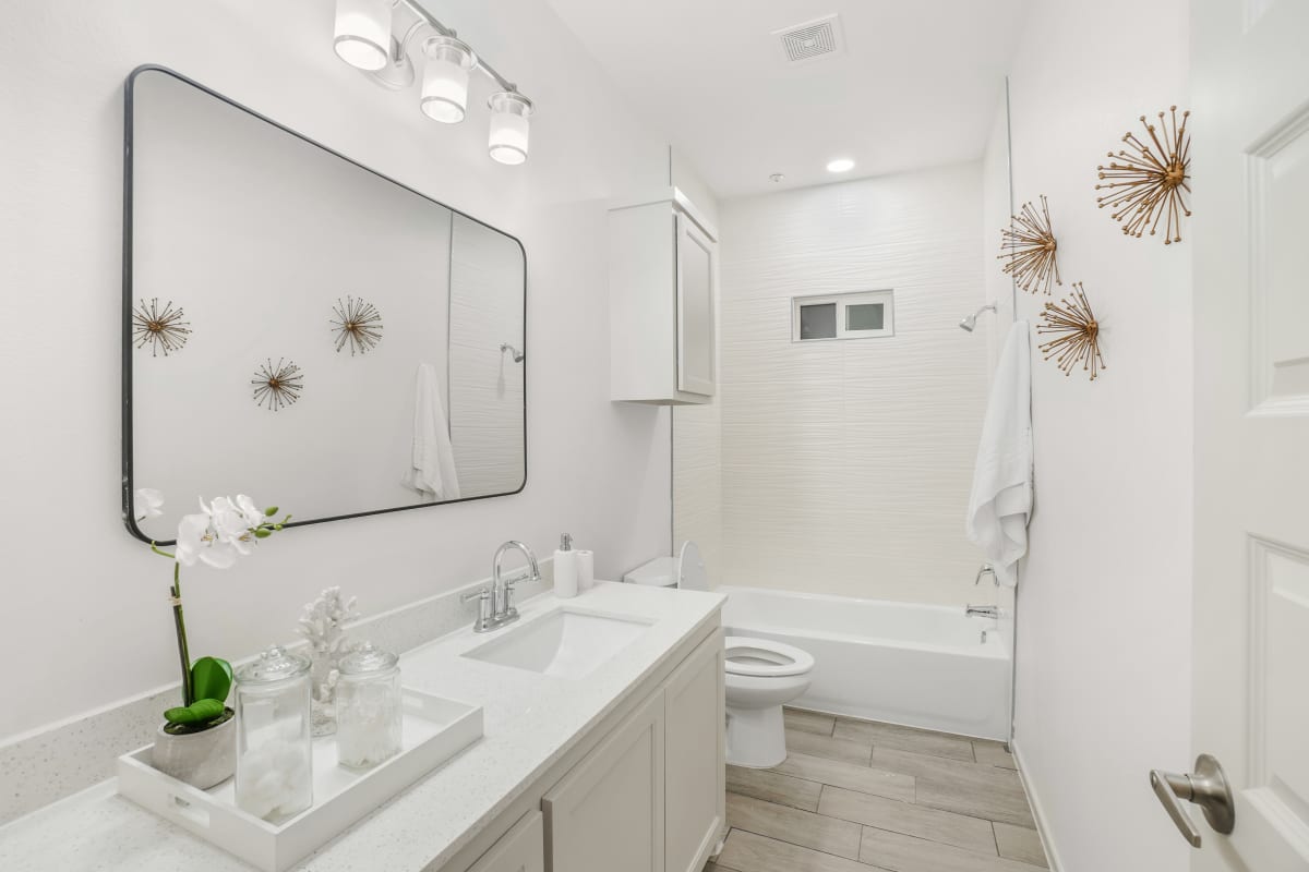 Sugar Mills full bathroom with wide mirror and bright vanity lighting