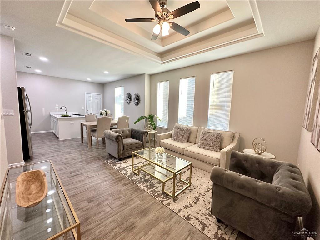 Furnished Dawson Estates living room under a tray ceiling, with the kitchen and dining table beyond
