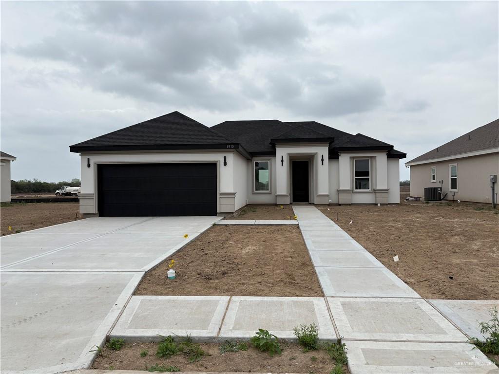 Single-story Hacienda Olivia home on Arden Street in Mercedes with a dark hip roof, stucco walls and a black garage door