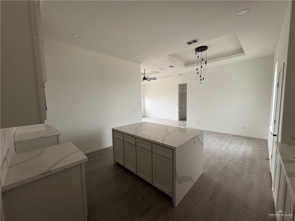 Hacienda Olivia kitchen island with marble-look countertops and a pendant light, looking into the living room