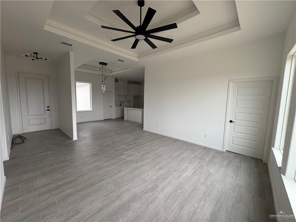 Hacienda Olivia living room with a tray ceiling and black ceiling fan, open to the kitchen