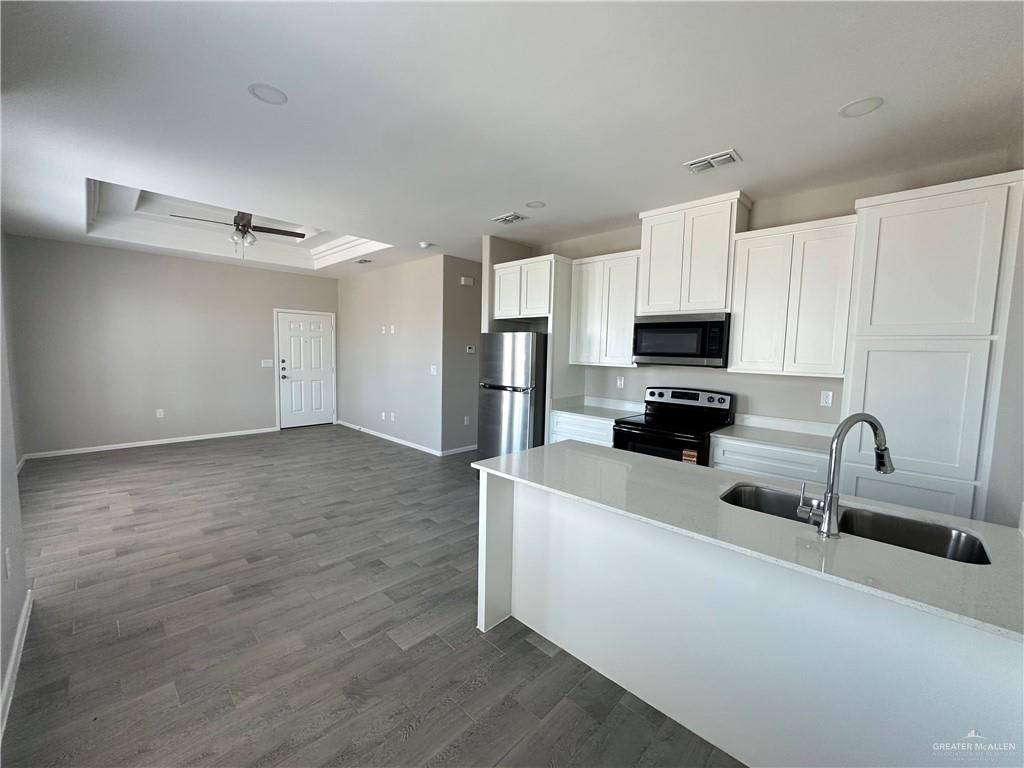 Riverside Tower kitchen island with a double sink, white cabinets and a black range, open to the living room