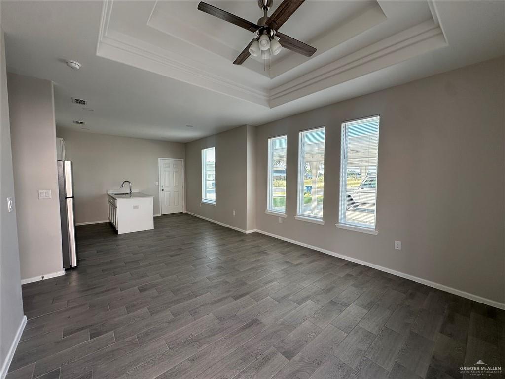 Riverside Tower living room with a tray ceiling, three tall front windows and the kitchen at the back