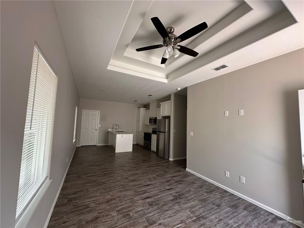 Heights at Alamo living room under a tray ceiling with a ceiling fan, open to the kitchen