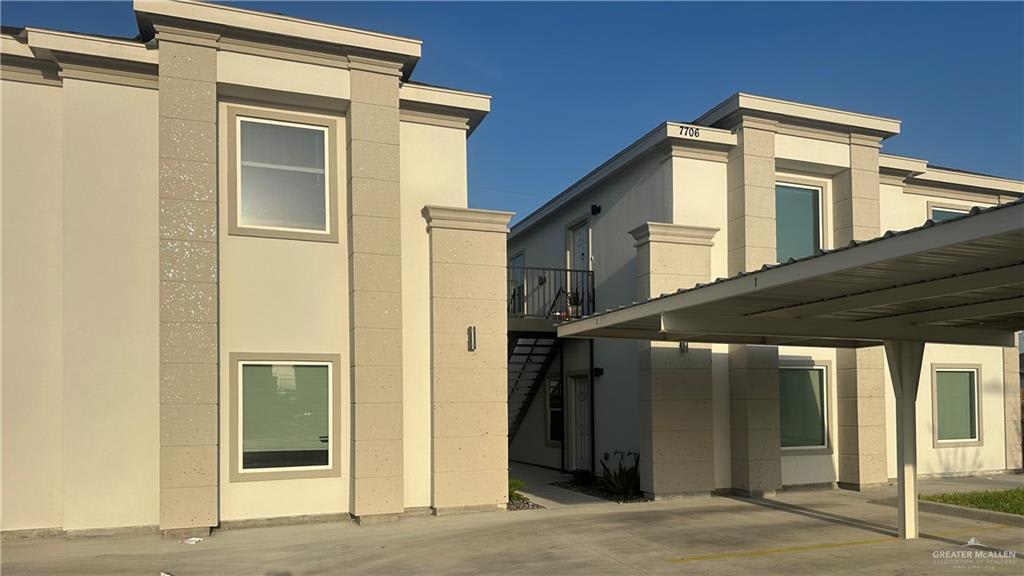 Two-story beige stucco fourplex at Vida in Mission, with a covered carport along one side