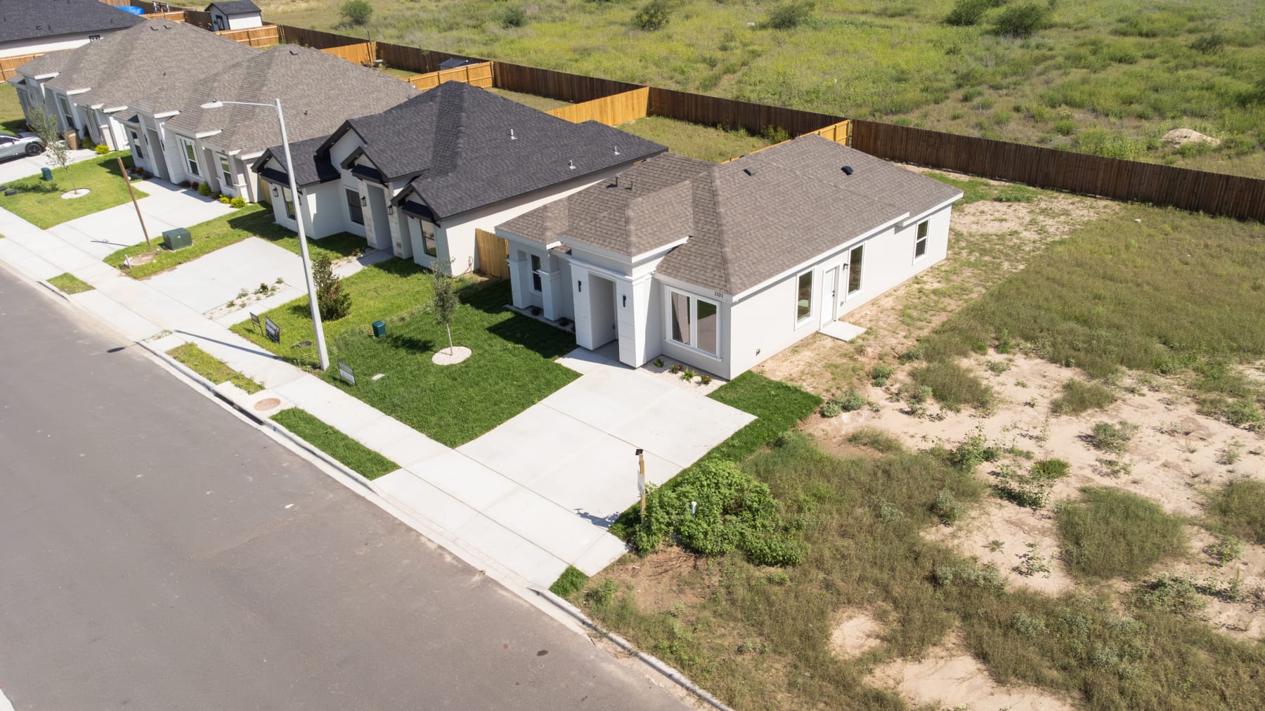 Aerial view of Oso Grande in Edinburg, Texas: a street of finished Four Pillars homes with landscaped lots
