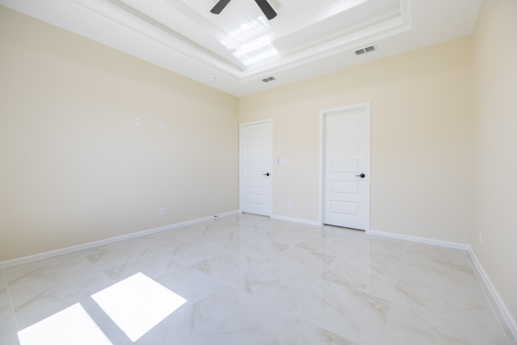 Unfurnished bedroom with closet and hallway doors under a tray ceiling