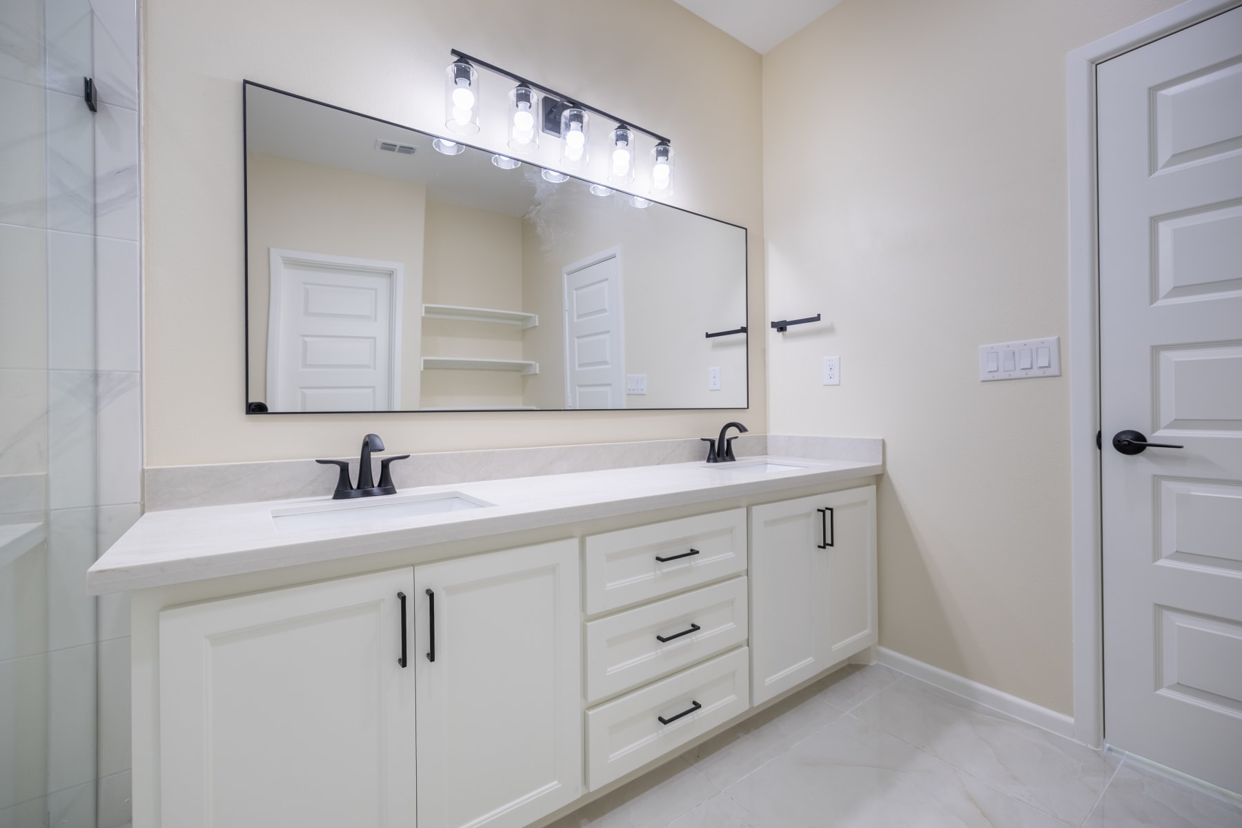 Double vanity with a wide framed mirror and a five-bulb bar light