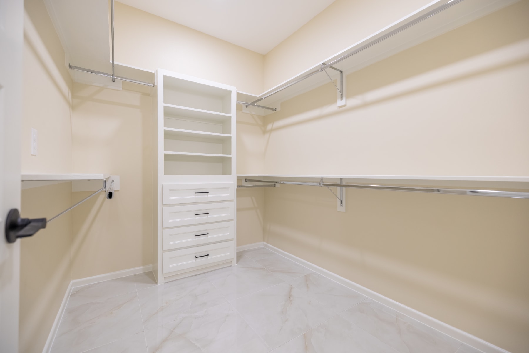 Walk-in closet with a built-in drawer tower and hanging rods on three walls