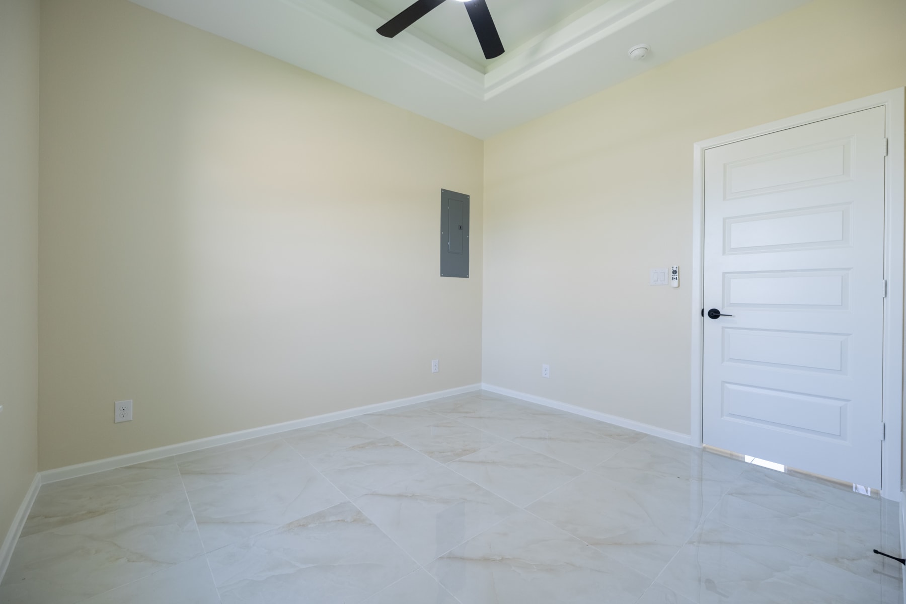 Unfurnished room with a tray ceiling fan and marble-look tile flooring