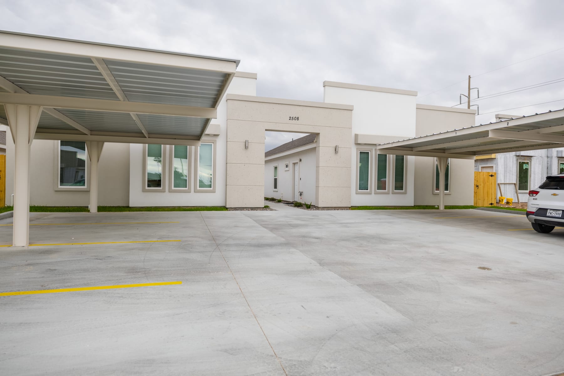 Front exterior elevation with arched entry and covered parking at Westwood Villas
