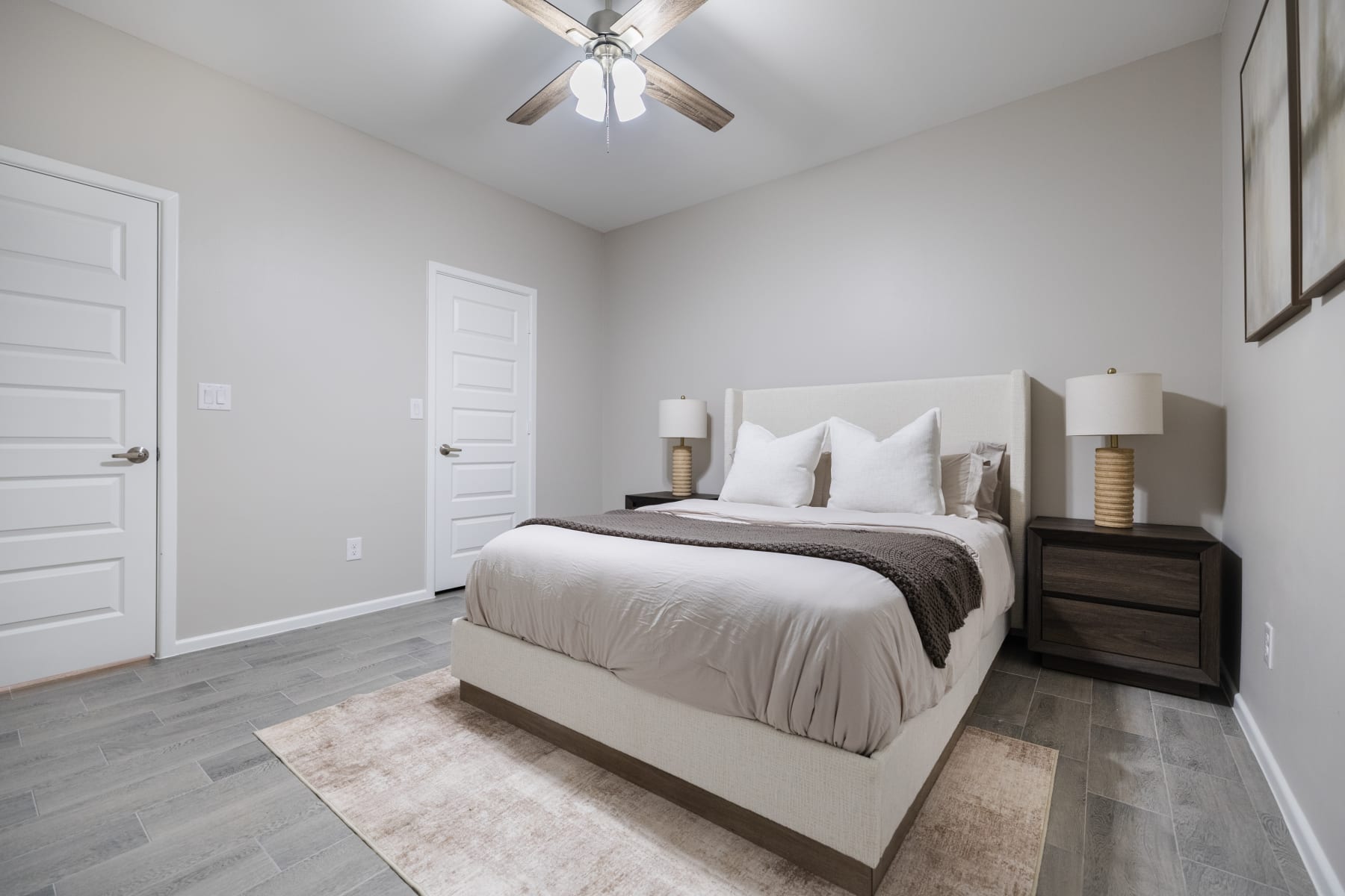 Bedroom with upholstered bed, wood-tone nightstands, and closet doors at Westwood Villas