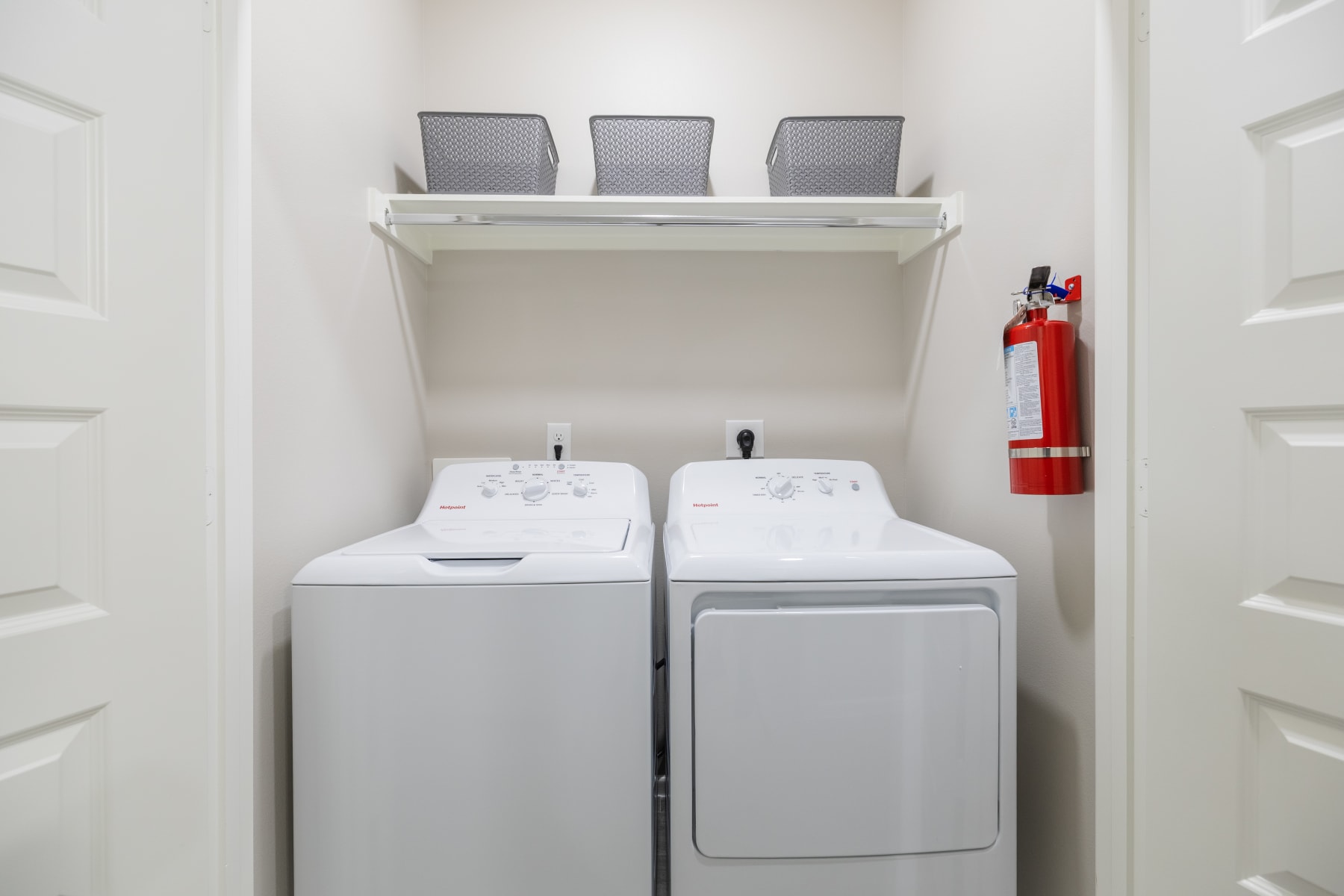 Laundry closet with side-by-side washer and dryer and a wall-mounted fire extinguisher at Westwood Villas