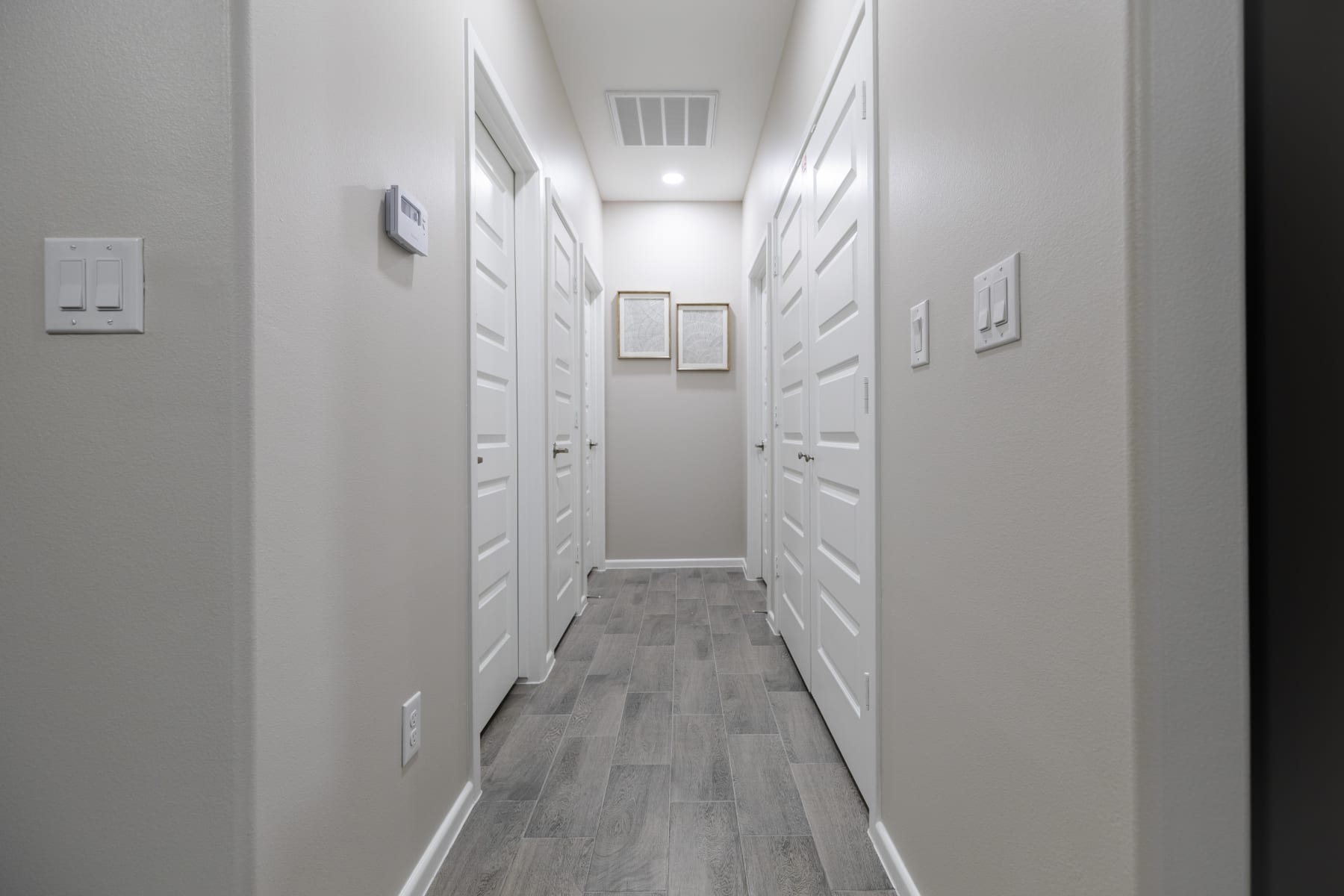Interior hallway with white paneled doors and framed art leading to bedrooms at Westwood Villas