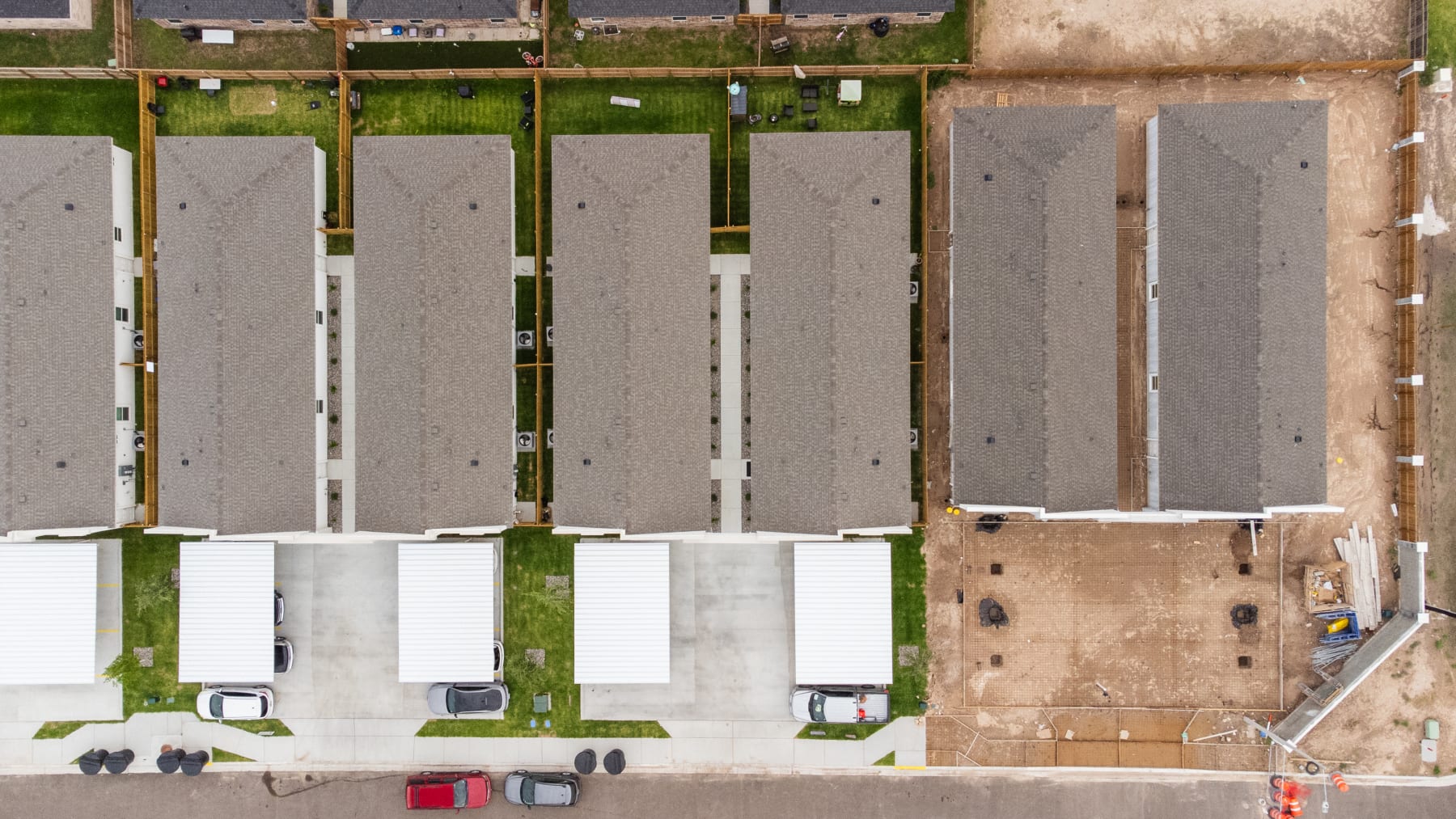 Overhead drone shot of Westwood Villas rooftops alongside an adjacent under-construction lot