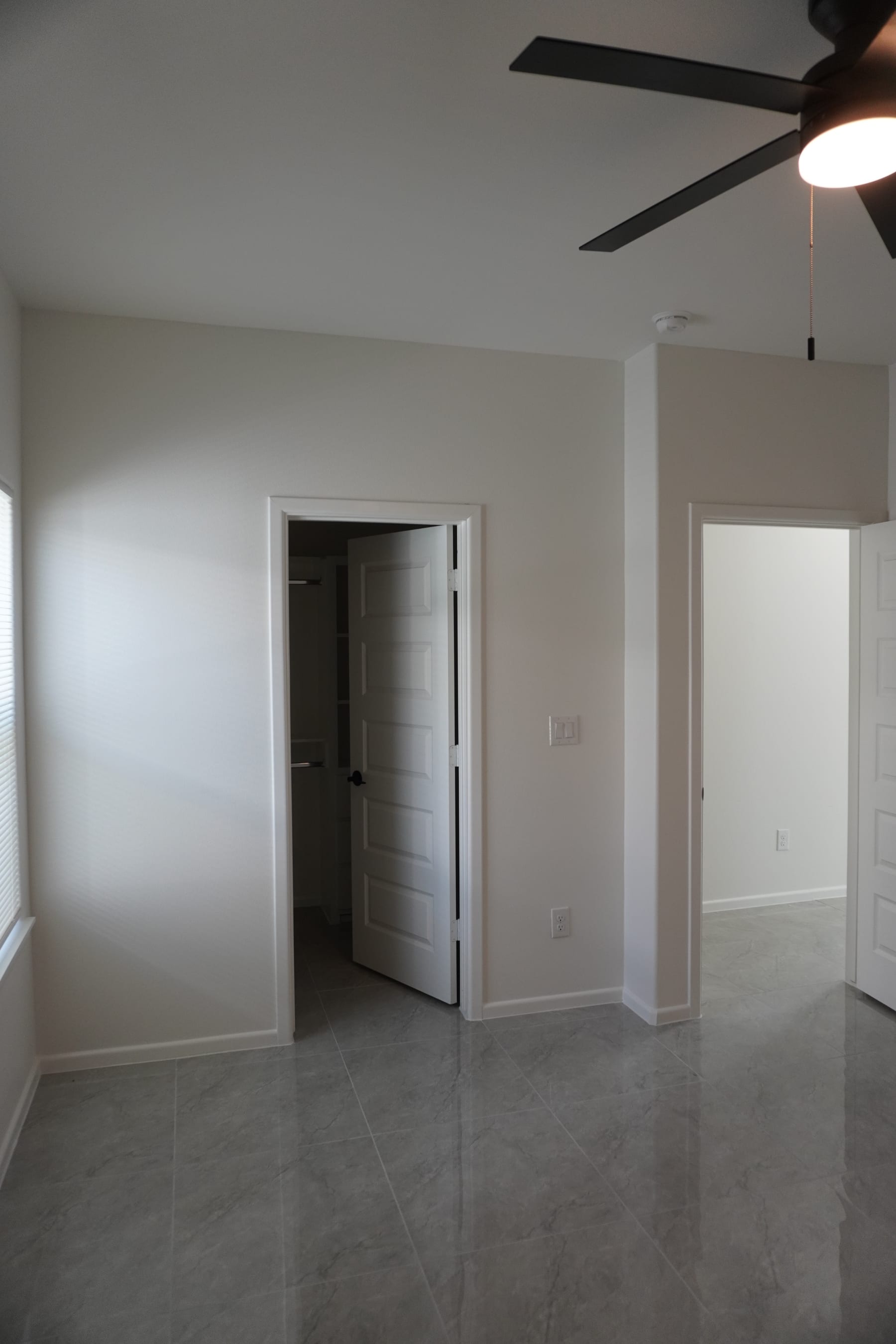 Spacious bedroom interior with high ceilings and fan