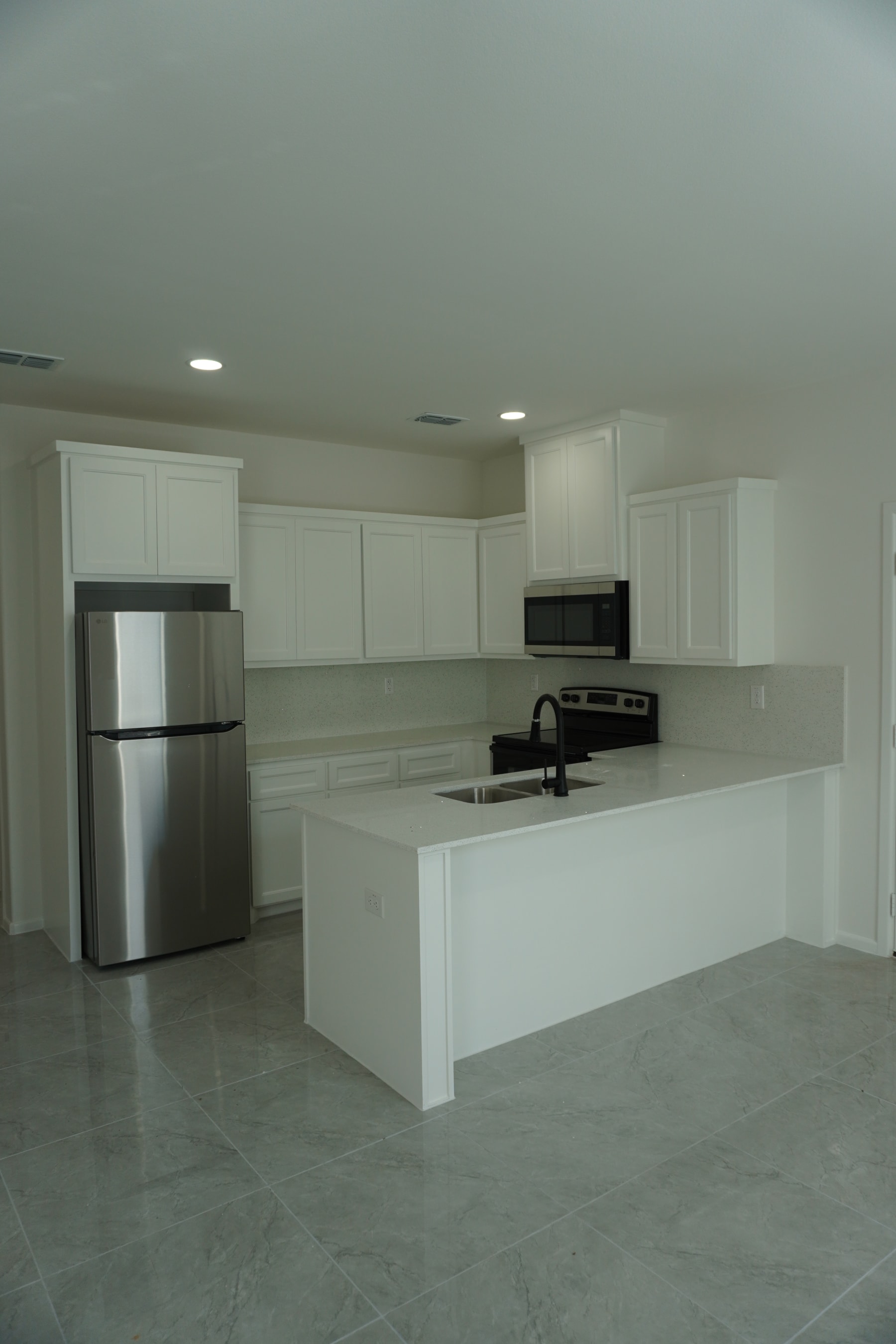 Alternative kitchen view showing grey cabinetry and appliances