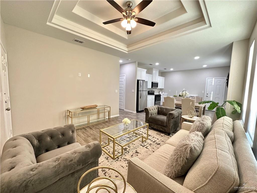 Dawson Estates living room staged with velvet armchairs and a glass coffee table, looking toward the kitchen