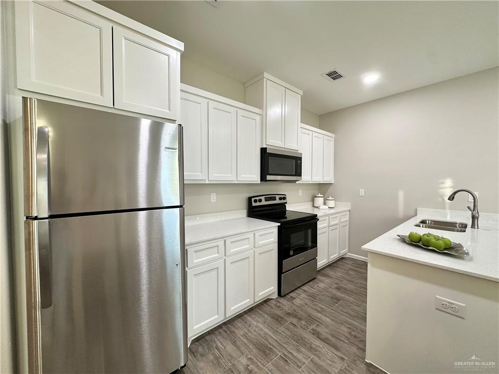 Dawson Estates kitchen with white cabinets, a stainless refrigerator and microwave, and a black electric range