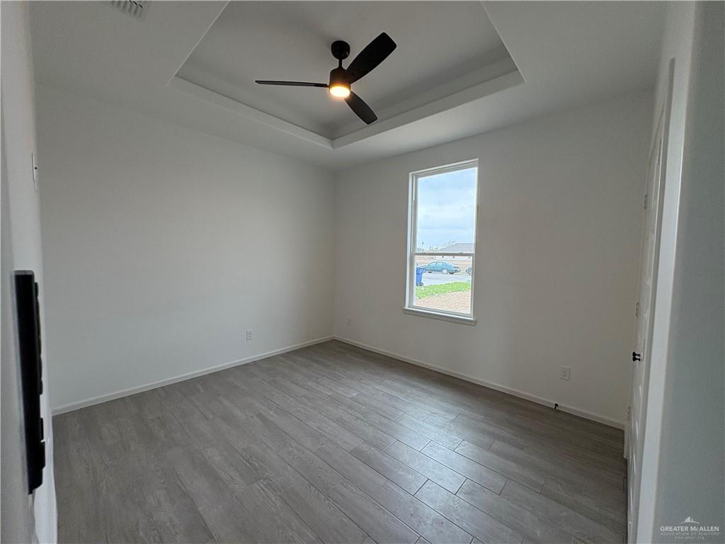 Hacienda Olivia bedroom with a tray ceiling and a window facing the street