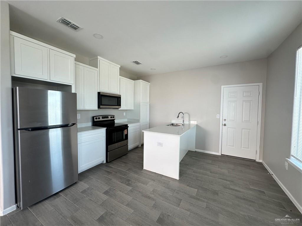 Riverside Tower kitchen with a stainless refrigerator, white cabinets and a small island beside the back door