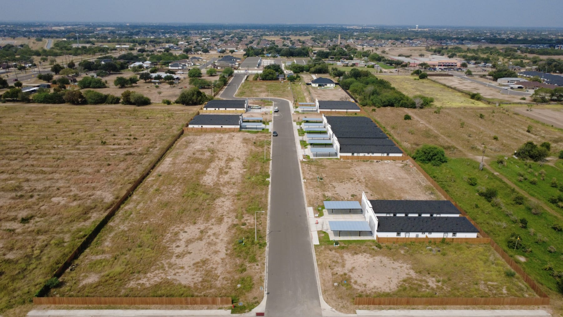 Aerial view along the Trosper Creek street, with fourplexes on one side and open homesites ahead